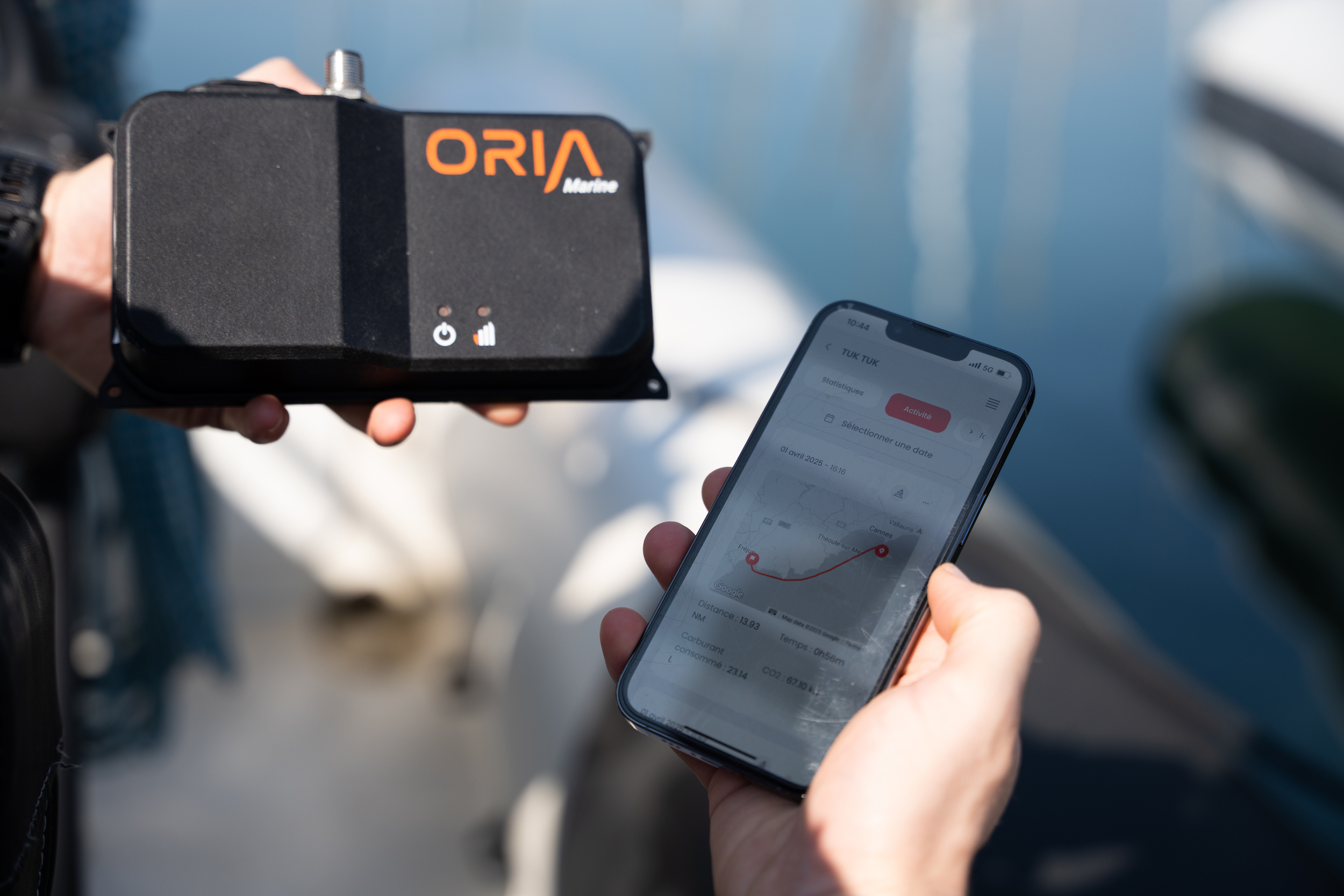 The Oria Box held in one hand, with the Oria mobile app showing a session on a phone in the other.